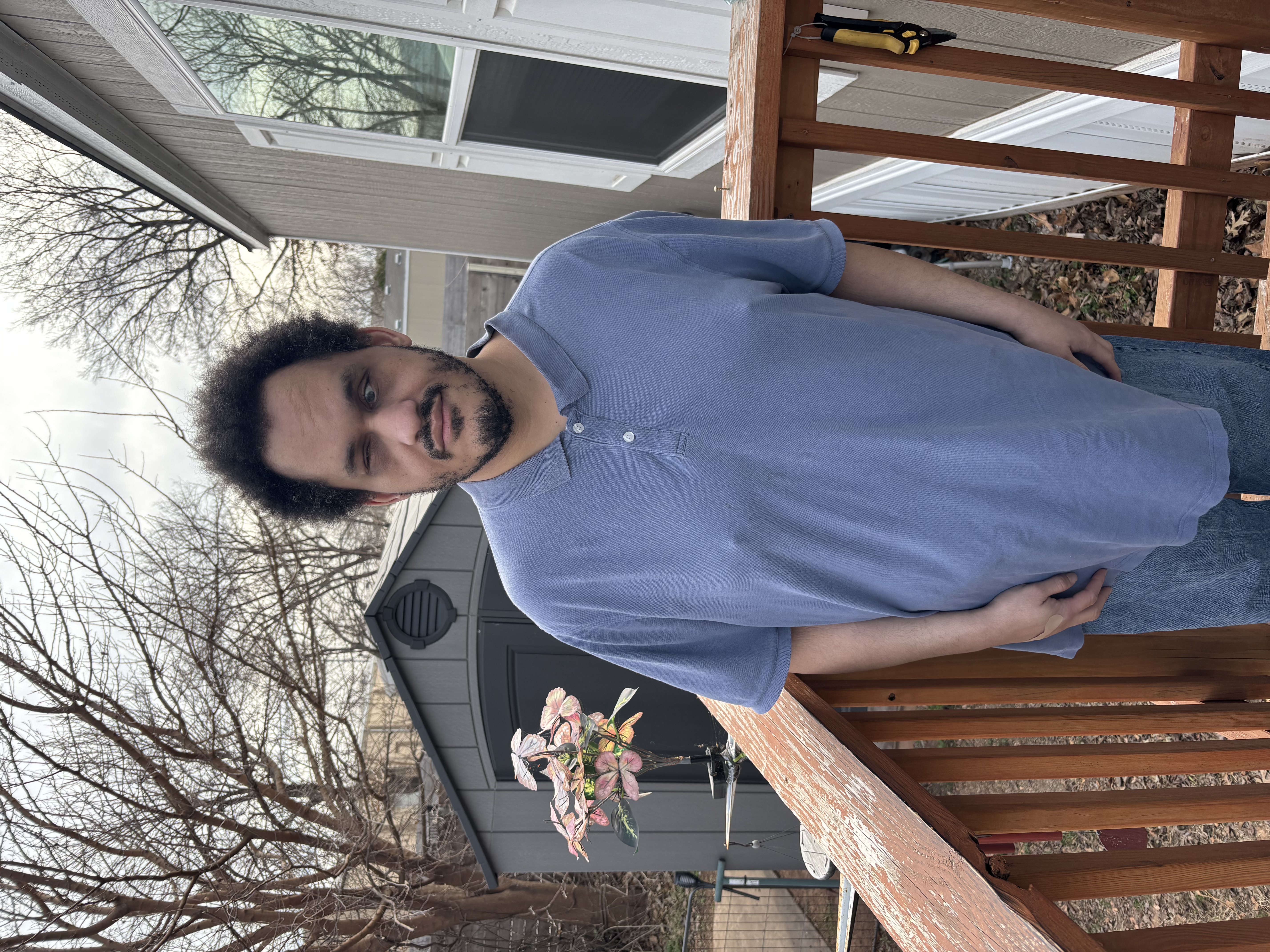 A photo of Daniel Chavez, the Founder of DChavezMusic: A man stands confidently on a wooden deck, enjoying the view of the outdoors.